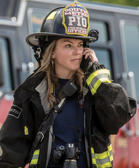 (2) Sometimes, you must use a smartphone as a phone while on scene. This public information officer (PIO) is operating in the offensive strategy and ready to capture important moments at a second’s notice. She is prepared with a helmet-mounted video camera rolling and a professional camera capable of capturing high-definition video and photographs within arm’s reach.