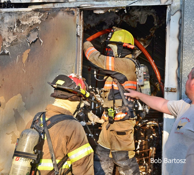 Firefighters manipulate a line inside the building where the pigs were housed