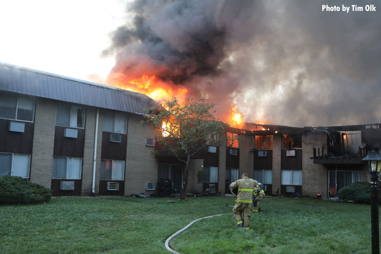 Firefighters approach a burning apartment building