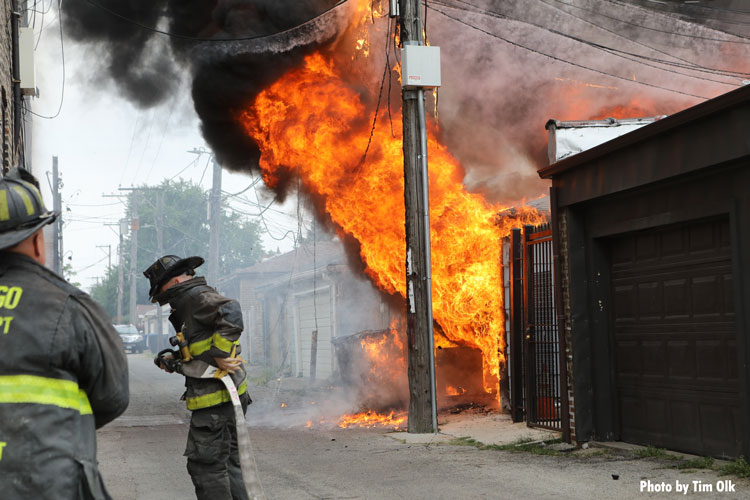 Chicago firefighter with a hoseline as fire rages in the background