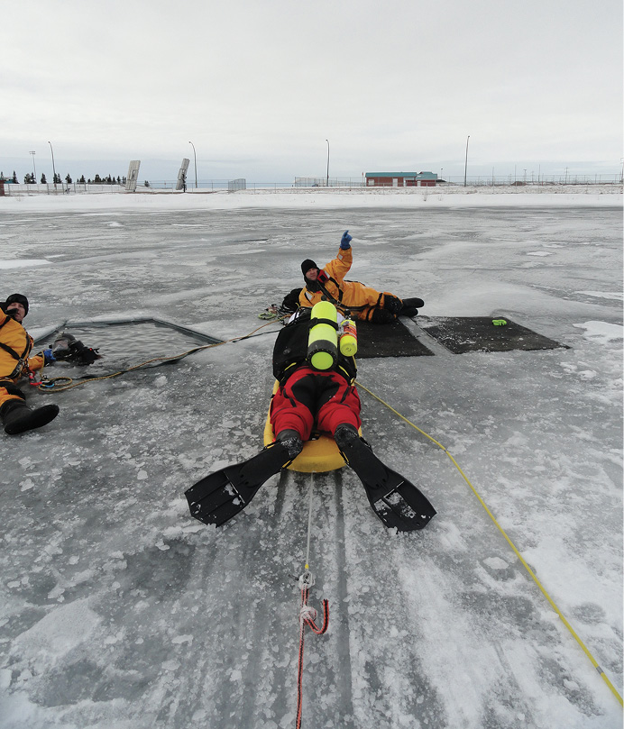 Surface ice rescue operations personnel were a key part of getting the PSD dive team divers and tenders out to the deployment hole. The primary tender (left), the diver, and the backup tender (right) are all connected into the leapfrogging system.