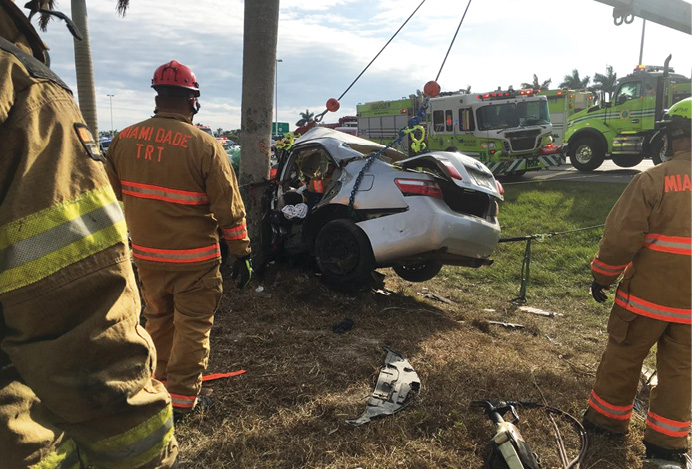 The rescuer is guiding and monitoring a control line or tie-back (with the yellow cover) opposite the points from which the vehicle is being pulled.