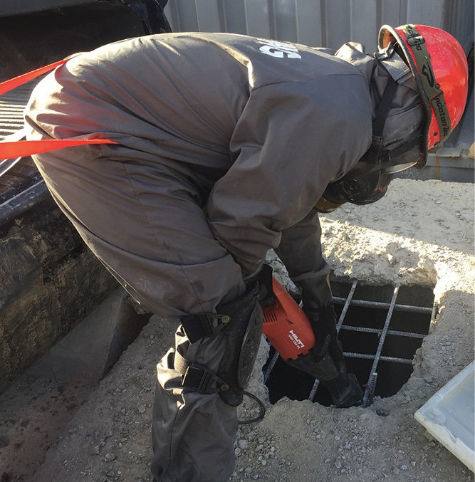 A reciprocating saw is used to cut the remaining rebar. Webbing is tied around the rescuer to keep him from falling into the hole.