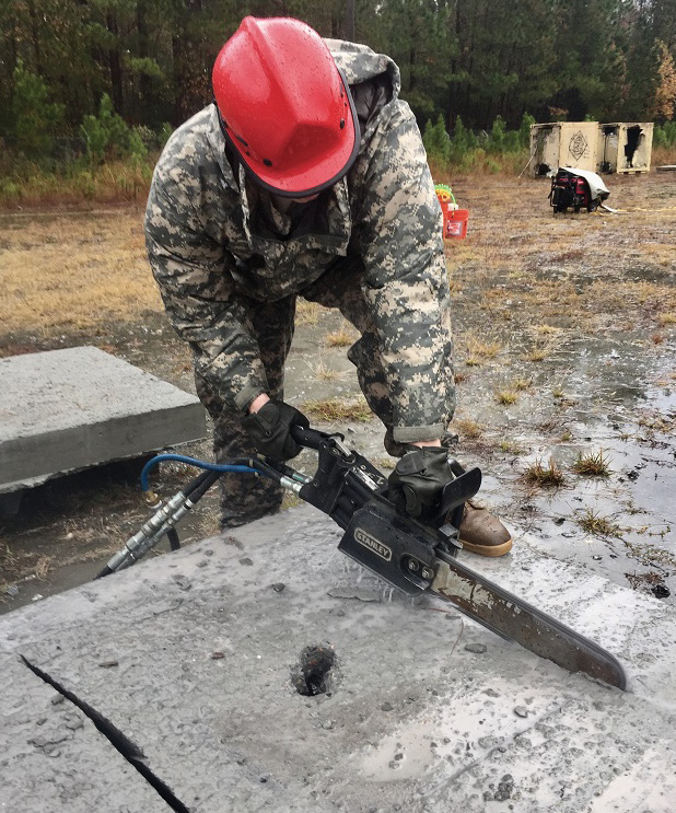 This soldier is making a pair of parallel bevel cuts with the hydraulic chain saw. Score lines were cut over the spray-painted lines for the 24-inch access point. The painted lines were washed away by rain.