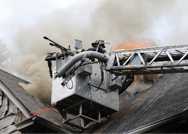 The tower ladder sticks the valley, granting access to multiple sections of the roof, allowing the firefighters to cut both sides from the bucket. (Photo by Patrick Dooley.)