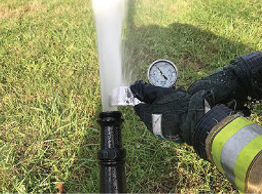 A firefighter uses a pitot gauge to measure the discharge pressure of a smooth bore nozzle. By comparing the nozzle pressure to the reading on the discharge gauge, pump operators can determine the amount of friction loss that must be accounted for when calculating a proper pump discharge pressure. 