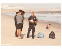 NYPD officers speak with teens on the beach.