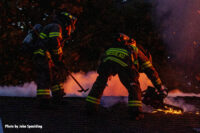 Two firefighters perform vertical ventilation at a house fire.