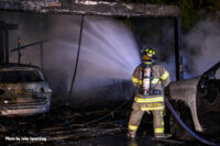 A firefighter administers water from a hoseline.