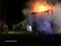 Firefighters operate a hoseline from the exterior.