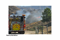 A fire truck with flames and smoke in the backdrop