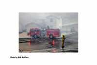 Firefighters direct a stream from a fire truck