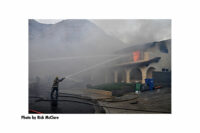 Firefighters direct streams onto a burning building during the Tick Fire