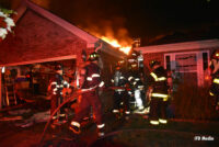 Firefighters advance a hoseline to attack fire in a home.