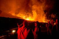 Firefighters confer while battling the Kincade Fire near Geyserville, Calif., on Thursday, Oct. 24, 2019. Portions of Northern California remain in the dark after Pacific Gas & Electric Co. cut power to prevent wildfires from sparking during dry and windy conditions. (AP Photo/Noah Berger)