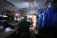 Maria's Restaurant manager Rich Fuxjager holds a battery powered lamp in the kitchen of Maria's restaurant as they continue to work with a limited menu following a power outage, Wednesday, Oct. 23, 2019, in Grass Valley, Calif. Lights went out across large portions of Northern California on Wednesday, as the state's largest utility began its second massive blackout in two weeks, citing the return of dangerous fire weather. (Elias Funez/The Union via AP)