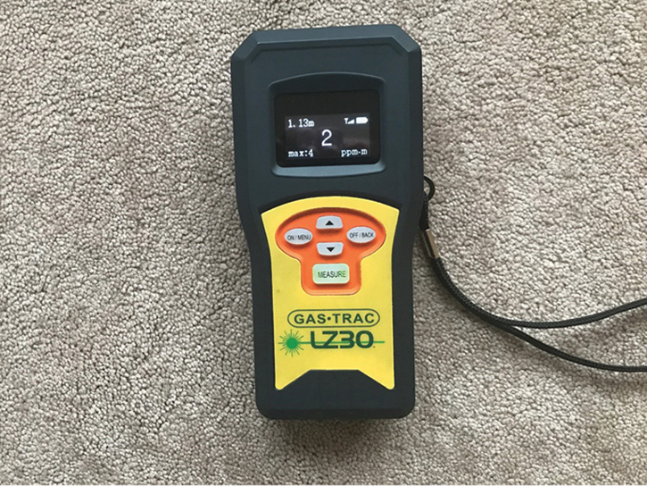 An example of a handheld TDLAS remote methane detector. The center display indicates a reading of 2 ppm-m (which is a typical background level of methane in air). The distance to the beam’s target is shown in the upper left corner of the display as “1.13 m” (meters). This instrument keeps the session’s peak reading in memory indicated at lower right as “Max: 4.” The reading strength and the battery indicator are at the upper right corner. This detector reads from 0 to 50,000 ppm-m of methane and responds in 0.10 seconds. Depending on the reflective surface of the laser’s target, it provides methane readings up to 100 feet away. The instrument also has an audible and a tactile (vibration) alarm, allowing the user’s eyes to remain on the target. The instrument’s internal rechargeable battery has a six-hour life cycle.