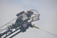 Firefighter on an aerial ladder directing a stream