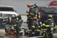 Firefighters with a variety of equipment, including a rotary saw and hoseline