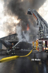 Firefighters put water on the warehouse fire