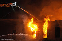 Aerial master stream administering water as fire vents from windows