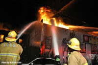 Los Angeles Fire Department firefighters aim hose streams on the fire.