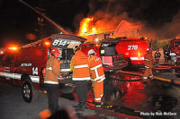 Battalion chief at the vehicle with flames rising from the building in the background