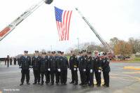 Firefighters beneath a huge U.S. Flag held by aerial ladders