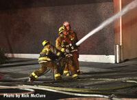 Firefighters control a stream on the exterior of the building.