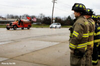 Firefighters stand at attention as the rig passes by.