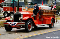 Firefighters drive an old fire truck bearing the remains of Fire Chief William Gitzke.