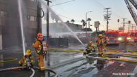 Firefighters control streams from the ground.