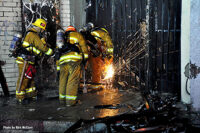 Firefighters use saws to force entry.