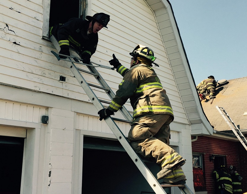 Firefighter on a ladder reaching out