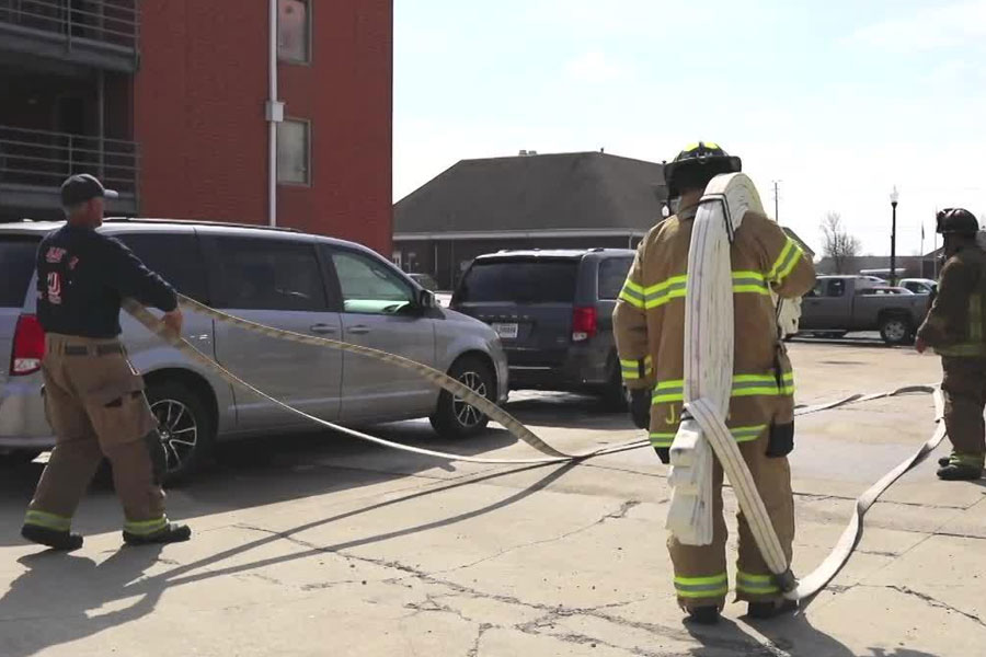 Firefighters flake out hoselines to navigate between parked cars