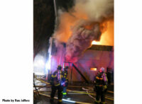 A view of fire and smoke coming out of the building with firefighters at work.