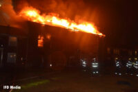 Flames burning through the roof of the building