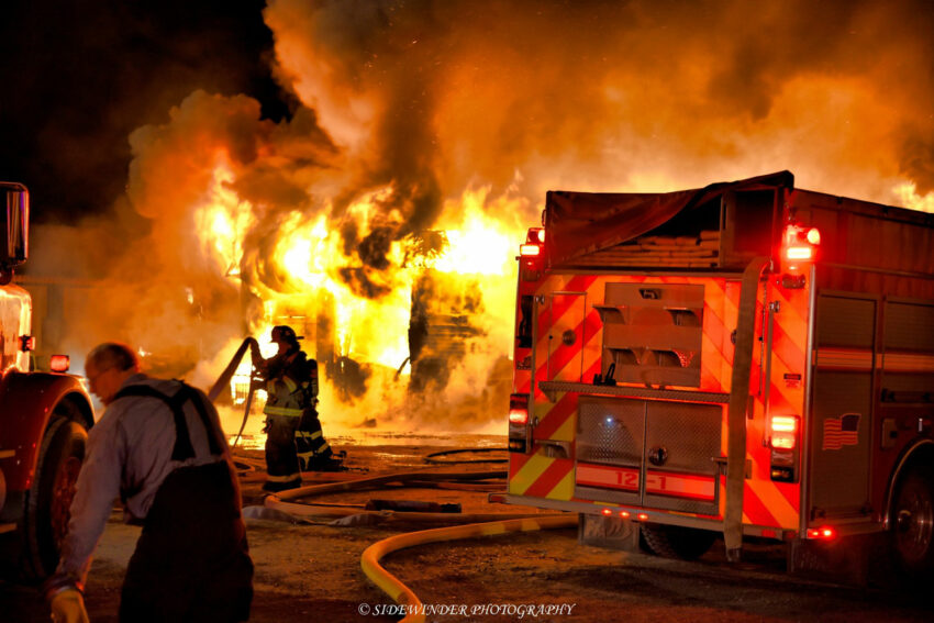 Firefighters pull hoselines from a rig, ready to combat the fire