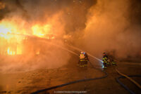 Firefighters aim two hoselines at the burning commercial garage