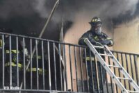 Firefighters on balcony with ladder and smoke