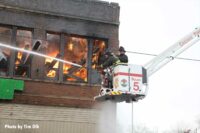 Firefighters in a bucket direct hose streams into the burning church building