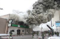 Chicago firefighters and hoselines at scene, with smoke billowing from the fire building