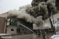 A firefighter directs a stream into the burning building