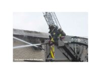 Firefighter in tower ladder bucket directing stream