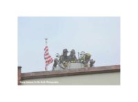 American flag and firefighters in a tower ladder bucket