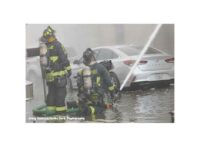 Firefighters direct hose streams from the ground