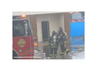 A firefighter directs another firefighter's attention on the fireground