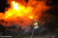 A firefighter aims a hose stream at burning brush in California