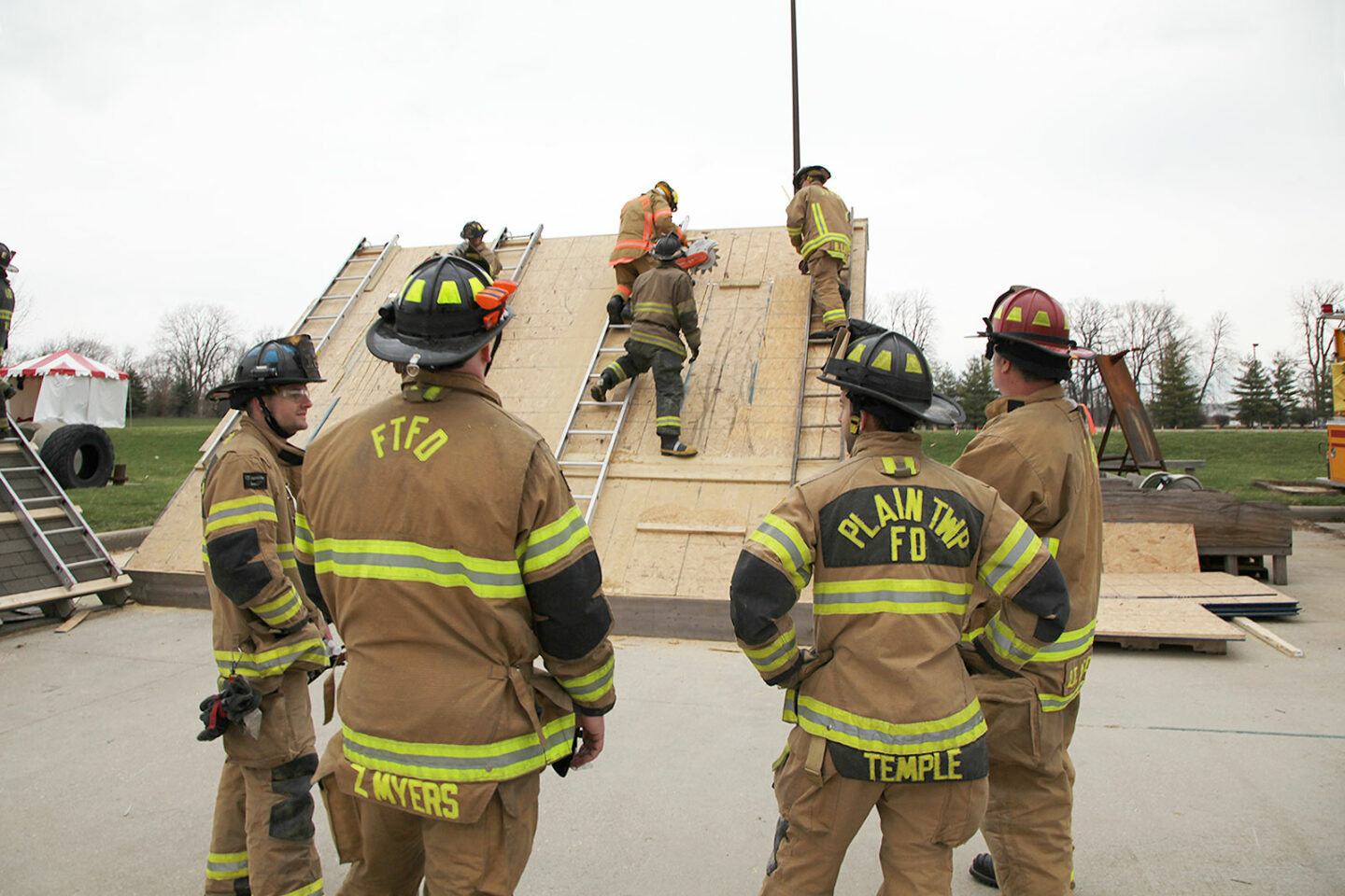 Firefighters with power saws training vertical ventilation on roof props