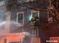 Boston firefighter working a hoseline on a portable ladder